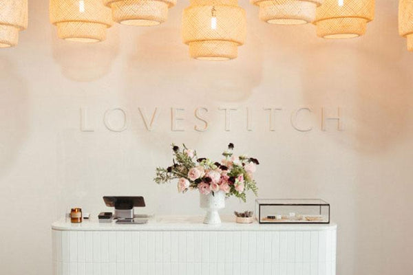 Lovestitch store in the Arts District of DTLA. White cash desk with pink flower arrangement.