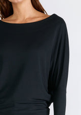 [Color: Black] A close up front facing image of a brunette model wearing a black soft ribbed knit pullover. With long dolman sleeves and a wide boat neck that can be worn on or off the shoulder. 