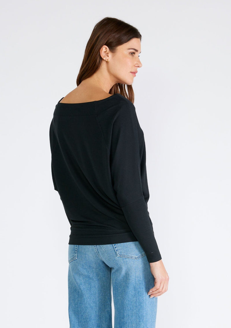 [Color: Black] A back facing image of a brunette model wearing a black soft ribbed knit pullover. With long dolman sleeves and a wide boat neck that can be worn on or off the shoulder. 