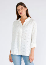 [Color: White] A half body front facing image of a brunette model wearing a classic white bohemian shirt crafted in embroidered eyelet cotton. With long sleeves, a classic collared neckline, and a button front. 
