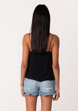 [Color: Black] A back facing image of a brunette model wearing a black bohemian camisole with adjustable spaghetti straps, a scoop neckline, a button up back, and lace detail. 