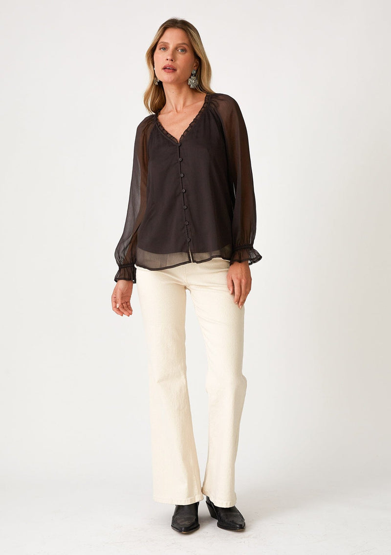 [Color: Chocolate] A front facing image of a blonde model wearing a bohemian fall blouse in a dark brown sheer chiffon. With long raglan sleeves, ruffled elastic wrist cuffs, a ruffled v neckline, and a self covered button front.