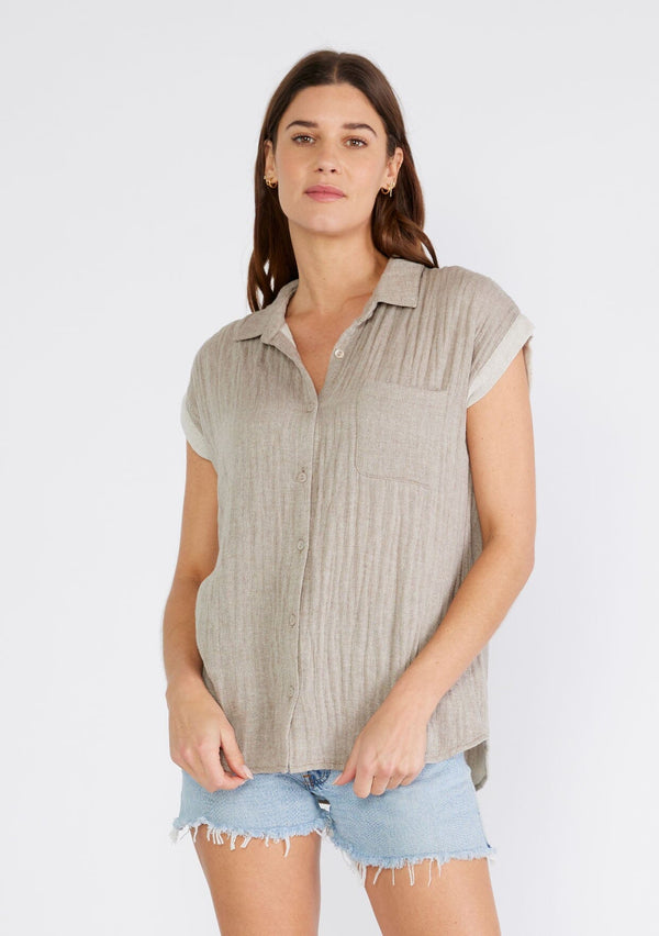 [Color: Taupe] A front facing image of a brunette model wearing a light brown short sleeve shirt crafted from soft cotton gauze. With a button up front, a collared neckline, a front patch pocket, and short contrast cap sleeves. 