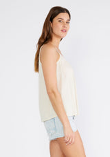[Color: Ivory] A side facing image of a brunette model wearing an ivory bohemian tank top with a scooped neckline, spaghetti straps, and a sheer lace racerback detail. 