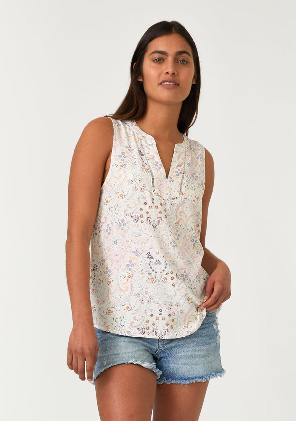 [Color: Natural/Pink] A front facing image of a brunette model wearing a relaxed bohemian resort tank top in a natural and pink floral print. With a v neckline, sheer lattice trim, and a soft hand feel. 