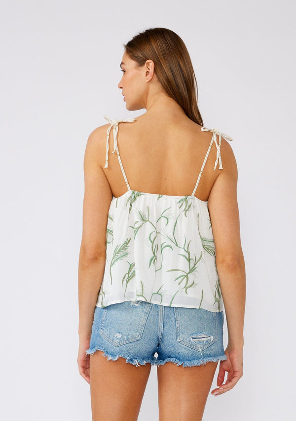 [Color: Off White/Green] A back facing image of a brunette model wearing a white cotton bohemian tank top with contrast green embroidery. With rope straps, adjustable shoulder ties, a ruffled neckline, and a flowy fit. 