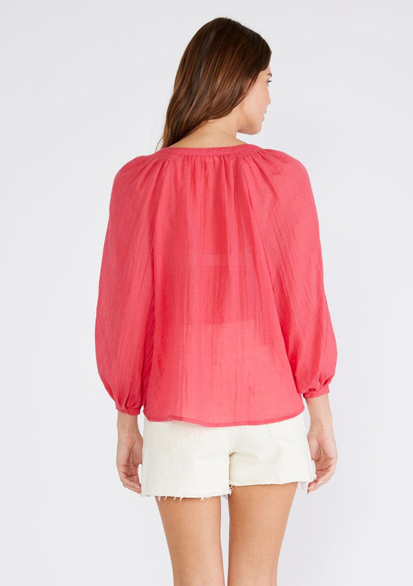 [Color: Coral] A back facing image of a brunette model wearing a red sheer bohemian blouse with long raglan sleeves, a round neckline, a button front, and a relaxed fit. 