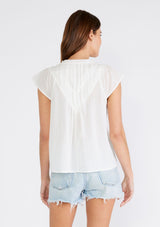 [Color: White] A back facing image of a brunette model wearing a white bohemian top crafted from lightweight cotton gauze. With short cap sleeves, a split v neckline, gathered details at the yoke, and a raw edge hem. 