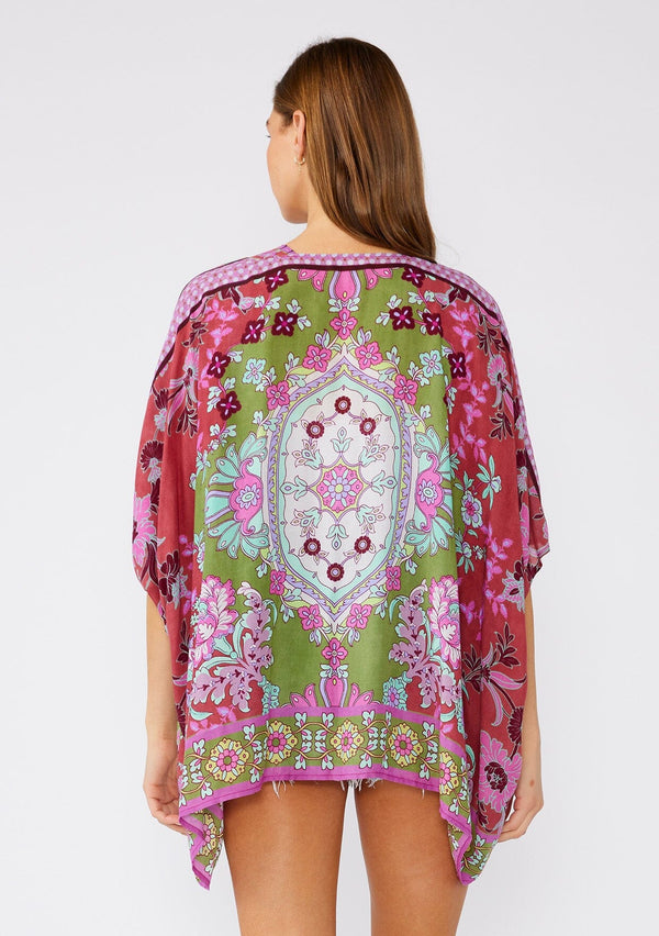 [Color: Green/Rose] A back facing image of a brunette model wearing a bohemian style kimono top in a green and pink floral print, with contrast border. A lightweight beach cover up with half length kimono sleeves, an open front, and a hip length hemline. 