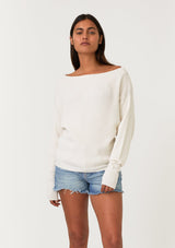 [Color: Natural] A front facing image of a brunette model wearing an off white waffle knit pullover sweater. With long sleeves, a relaxed fit, and a wide neckline that can be worn off the shoulder.
