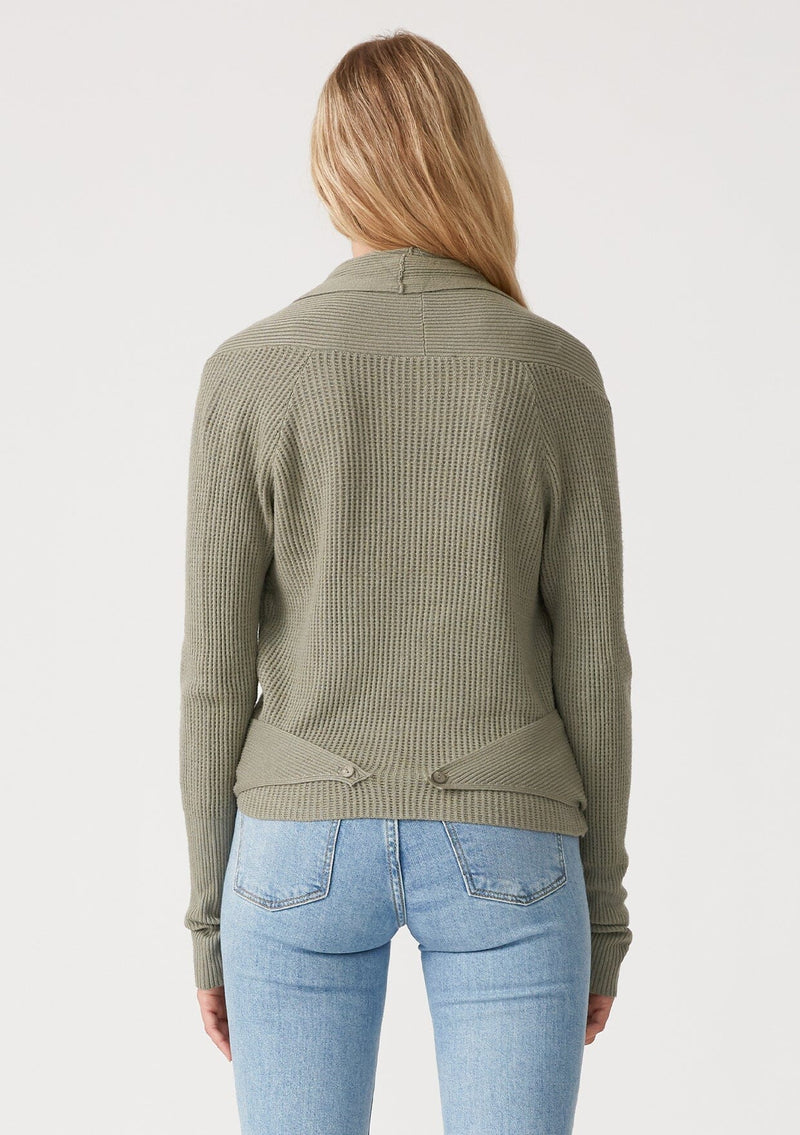 [Color: Olive] A back facing image of a blonde model wearing an olive green waffle knit wrap sweater with long sleeves, a v neckline, and a button closure at the back. The long ties can be styled in multiple ways. 