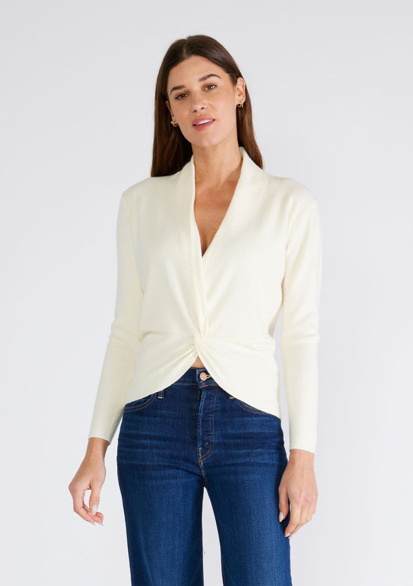 [Color: Cream] A front facing image of a brunette model wearing a cream colored knit sweater top. With a slim fit, long sleeves, a deep v neckline, and a twist front detail. 