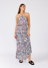 [Color: Natural/Dusty Blue] A full body front facing image of a brunette model wearing a stunning sleeveless beach maxi dress designed in a blue bohemian print. With a halter neckline and adjustable tie at the back neckline, an elastic waist, and a long flowy skirt with a ruffle trimmed tiered hemline. 