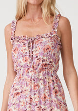 [Color: Dusty Purple/Taupe] A close up front facing image of a blonde model wearing a pink and purple floral print maxi dress. With ruffled tank top straps, a ruffle trimmed square neckline, an elastic waist, a tiered long skirt, and a lace up top. 