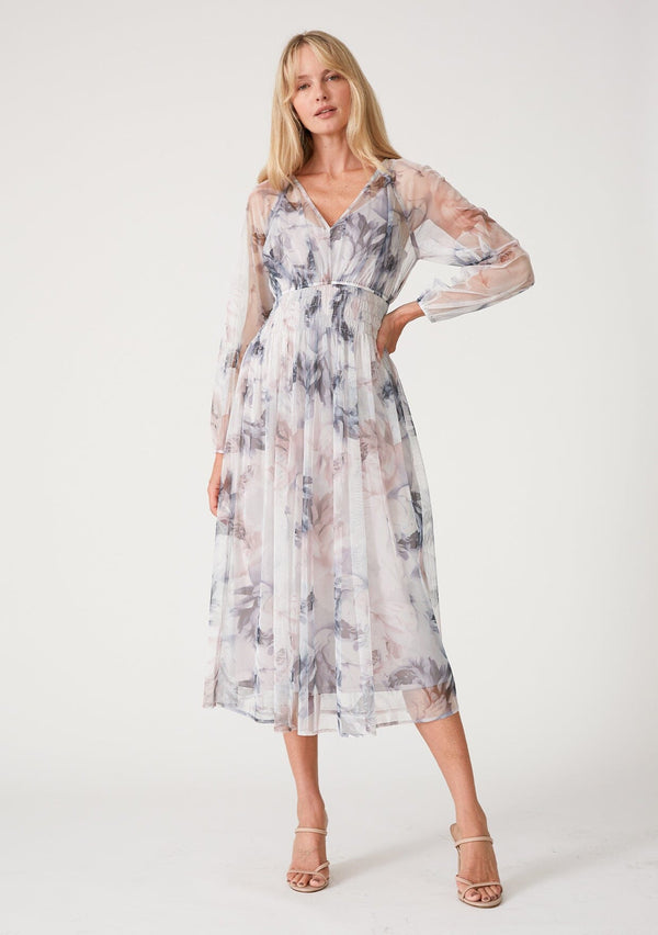 [Color: Grey/Dusty Rust] A front facing image of a blonde model wearing a bohemian resort maxi dress crafted from sheer mesh tulle, designed in a grey and dusty rust floral print. With long raglan sleeves, a v neckline, and a smocked elastic waist. 