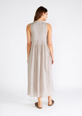 [Color: Grey] A back facing image of a brunette model wearing a lightweight bohemian sleeveless maxi tent dress in grey. With a v neckline, pleated details, and side pockets.