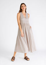 [Color: Grey] A front facing image of a brunette model wearing a lightweight bohemian sleeveless maxi tent dress in grey. With a v neckline, pleated details, and side pockets.