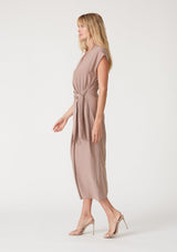 [Color: Mocha] A side facing image of a blonde model wearing a light brown maxi length wrap dress. With short cap sleeves, a deep v neckline, and a side tie waist closure. 