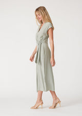 [Color: Pistachio] A side facing image of a blonde model wearing a light green maxi length wrap dress. With short cap sleeves, a deep v neckline, and a side tie waist closure. 