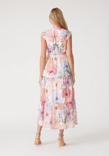 [Color: Ivory/Natural] A back facing image of a blonde model wearing a pink floral maxi dress. With short cap sleeves, a v neckline, a button front, an empire waist, a ruffle trimmed tiered skirt, and a drawstring waist with tassel ties. 