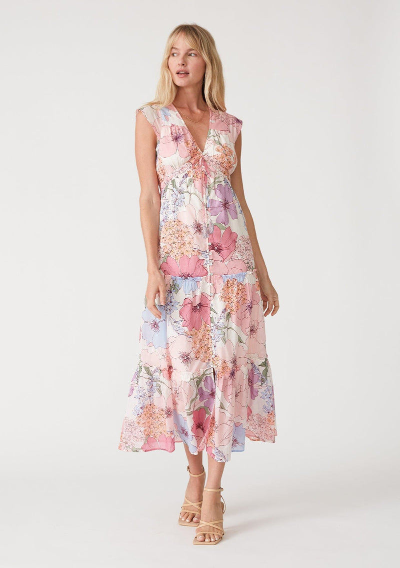 [Color: Ivory/Natural] A front facing image of a blonde model wearing a pink floral maxi dress. With short cap sleeves, a v neckline, a button front, an empire waist, a ruffle trimmed tiered skirt, and a drawstring waist with tassel ties. 