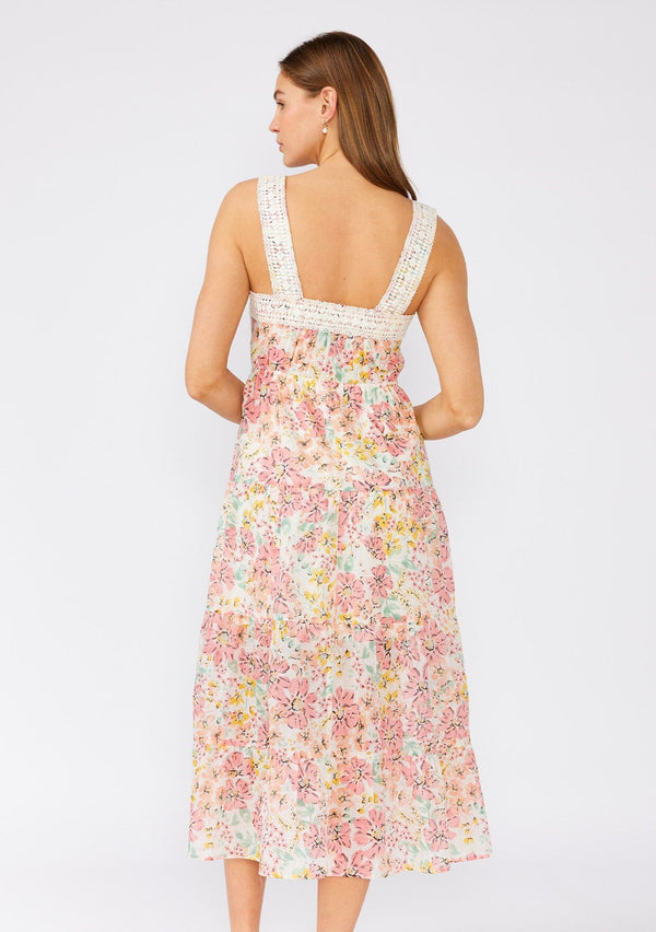 [Color: Natural/Peach Blossom] A back facing image of a brunette model wearing a bohemian pink floral mid length dress. A sleeveless summer dress with adjustable tank top straps, a square neckline, a flowy tiered skirt, an adjustable drawstring tie waist, and lace trim. 