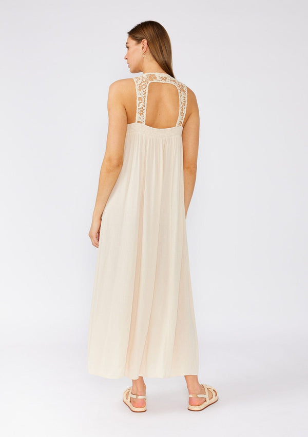 [Color: Natural] A back facing image of a brunette model wearing a flowy sleeveless bohemian maxi dress in ivory. With a crochet top, a scooped neckline, and an open back detail. 