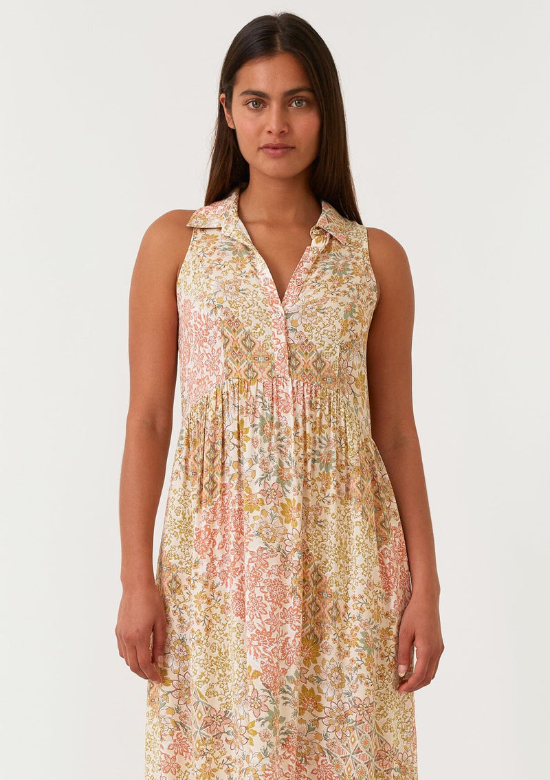 [Color: Dusty Peach/Rust] A close up front facing image of a brunette model wearing a bohemian sleeveless maxi dress designed in a peach and rust floral print. With a collared neckline, a self covered button front top, a long tiered skirt, and side pockets. 