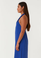 [Color: Cobalt] A half body side facing image of a brunette model wearing a bright cobalt blue halter maxi dress. With a twist front halter neckline, adjustable tie, front slit, and sexy open back. Perfect for the beach or the pool. 