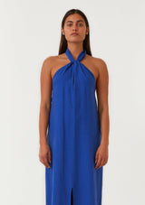 [Color: Cobalt] A half body front facing image of a brunette model wearing a bright cobalt blue halter maxi dress. With a twist front halter neckline, adjustable tie, front slit, and sexy open back. Perfect for the beach or the pool. 
