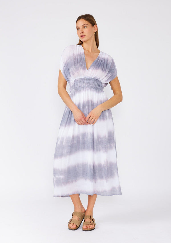 [Color: Off White/Grey] A front facing image of a brunette model wearing a bohemian mid length spring dress in a white and grey stripe. With short dolman sleeves, adjustable ties at the shoulder, an elastic waist, and a double v neckline in the front and back. 