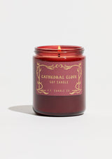 A fall and holiday candle in a burgundy glass jar labeled “P.F. Candle Co. Cathedral Clove.”