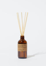 An amber glass diffuser bottle with a kraft label and rattan reeds. The Gold Coast Diffuser from PF Candle.