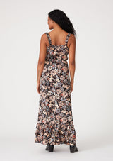 [Color: Black/Dusty Blue] A back facing image of a brunette model wearing a bohemian sleeveless maxi dress in a black and dusty blue floral print. With ruffled tank top straps, a tiered long skirt, an elastic waist, a square neckline, and a lace up tie front top. 
