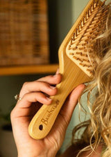 Person using a wooden hairbrush from Bamboo Switch.