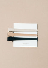 [Color: Cacao] A set of three long alligator style metal hair clips in black, mocha brown, and cream.