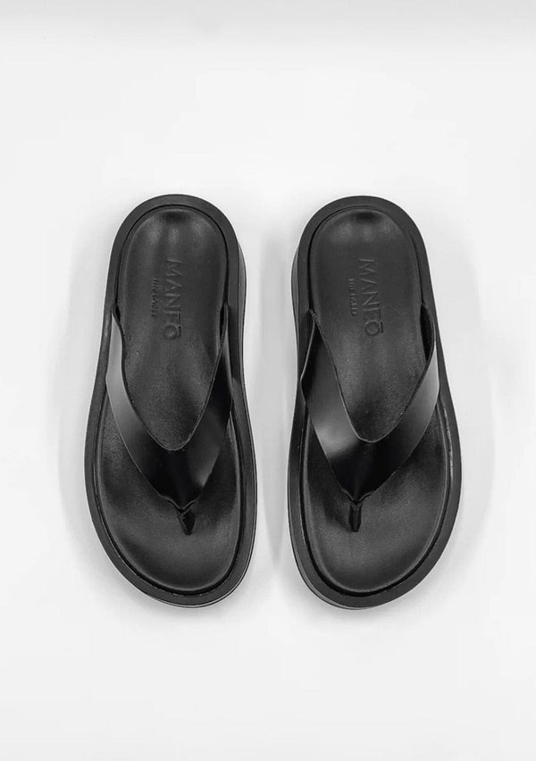 [Color: Black] A minimalist pair of black thong platform leather sandals. 