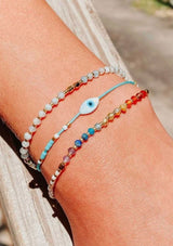 An adjustable healing bracelet, crafted on a durable nylon cord with gold-plated hardware and chakra colored natural gemstones. Designed by Kindred Row.