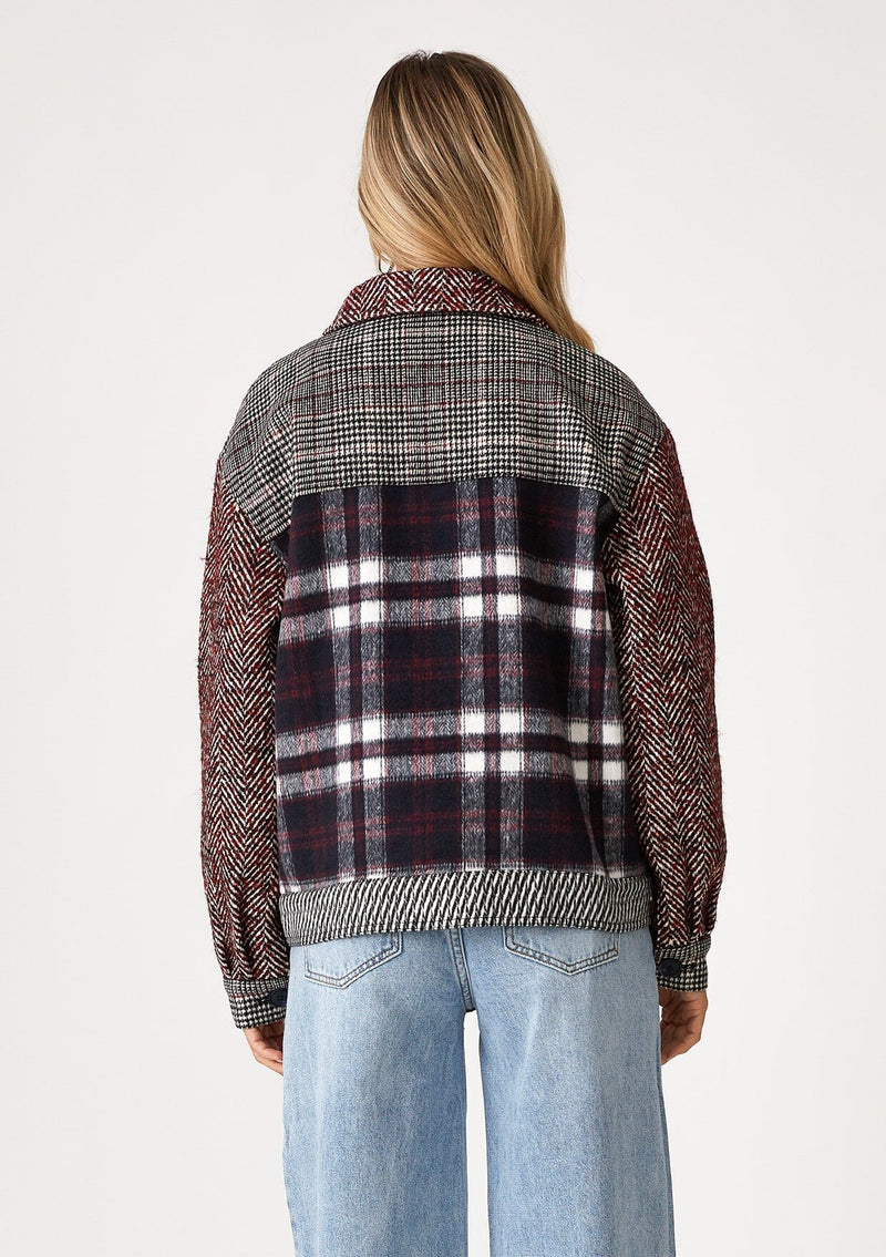 [Color: Wine/Navy] A back facing image of a blonde model wearing a classic shirt jacket in a wine red and navy blue patchwork plaid. A soft fall and winter jacket with long sleeves, front patch flap pockets, a collared neckline, a button up front, and side pockets. 