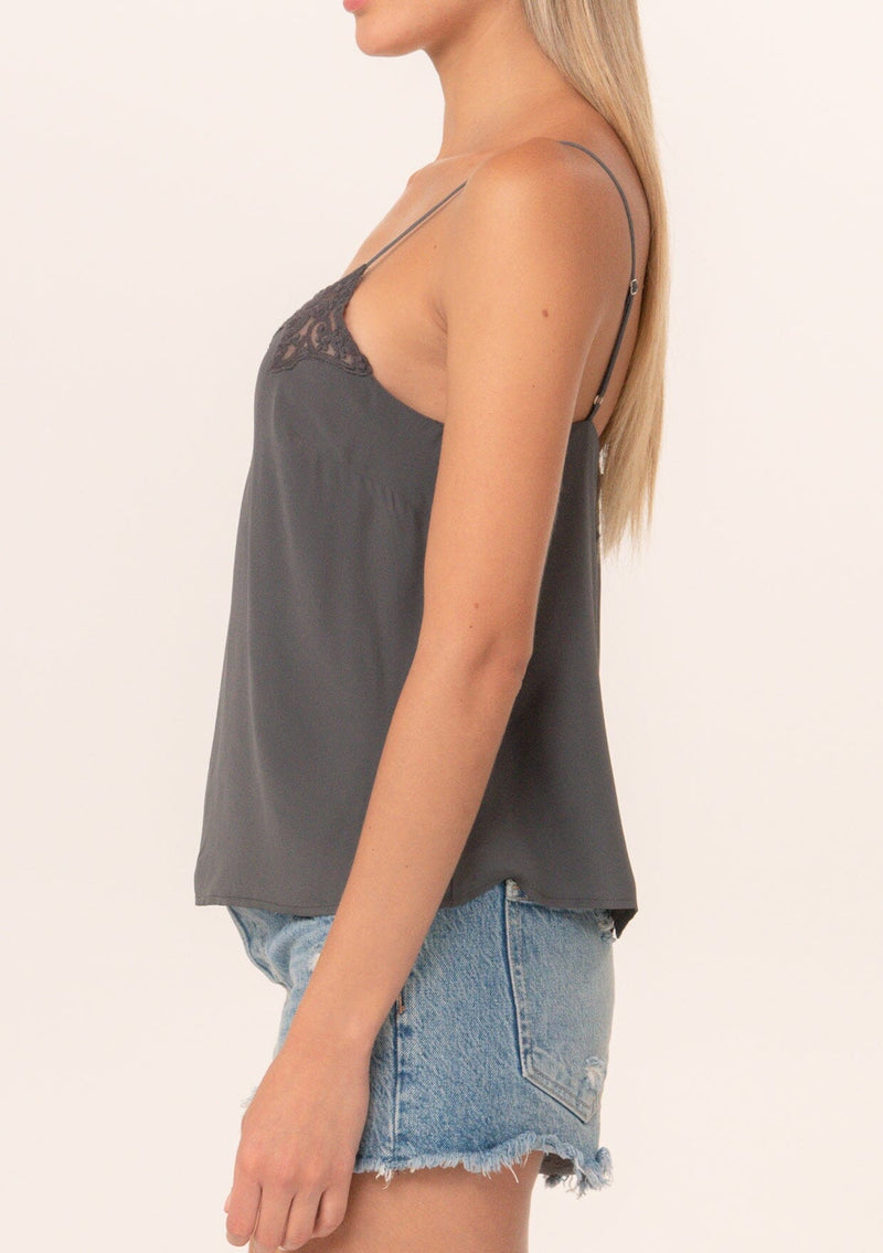 [Color: Pewter] A close up side facing image of a blonde model wearing a grey bohemian camisole with adjustable spaghetti straps, a scoop neckline, a button up back, and lace detail.