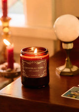 A fall and holiday candle in a burgundy glass jar labeled “P.F. Candle Co. Cathedral Clove.”