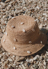 A raffia bucket hat with sewn in cowry shells.