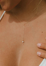 A dainty fourteen karat gold plated on sterling silver necklace with a drop accent and freshwater pearl. Hypoallergenic and made in the USA.