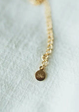 A dainty fourteen karat gold plated on sterling silver necklace with a drop accent and freshwater pearl. Hypoallergenic and made in the USA.