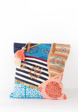 [Color: Denim Multi] A mixed media patchwork tote bag with leather handles and over size pom detail. 