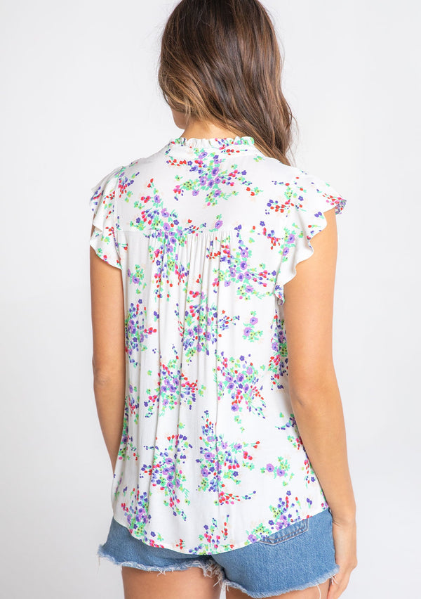 [Color: Ivory/Violet] A model wearing a bohemian white short flutter sleeve button front top in a purple floral print. 