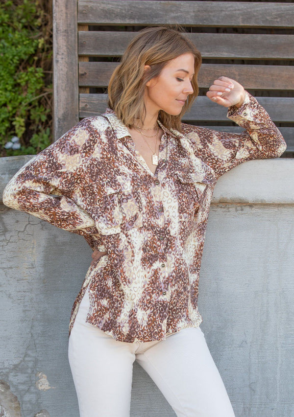 [Color: Mocha Sand] A soft and satiny button up shirt is featured in an allover watercolor leopard print. Featuring double front safari pockets and breezy side vents.