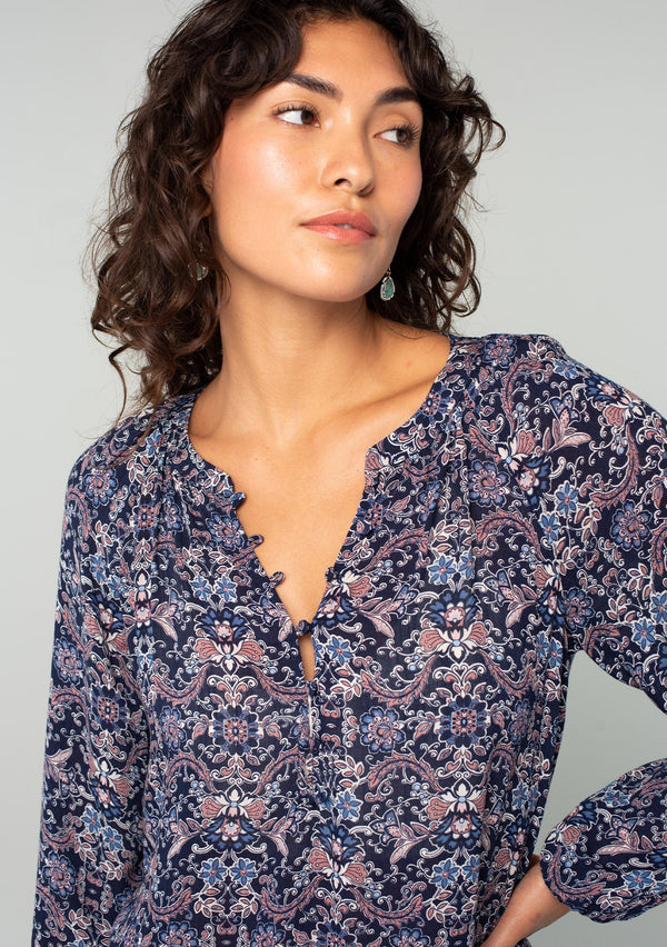 [Color: Navy/Tan] A close up front facing image of a brunette model wearing a navy and tan paisley print peasant top. A classic flowy bohemian blouse with long sleeves, a loop button front, and elastic wrist cuffs. 
