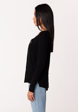 [Color: Black] A side facing image of a model wearing a black micro rib long sleeve tee with a v neckline and neck ties. 