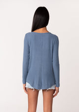 [Color: Denim] A back facing image of a model wearing a blue micro rib long sleeve tee with a v neckline and neck ties. 